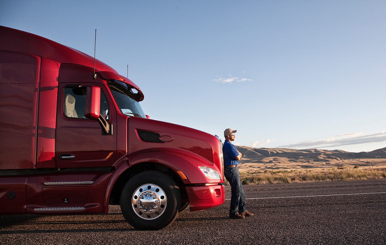 Driver standing beside a tractor on a rural highway
